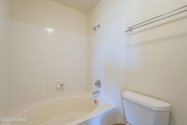 bathroom featuring toilet,  shower combination, and a textured wall