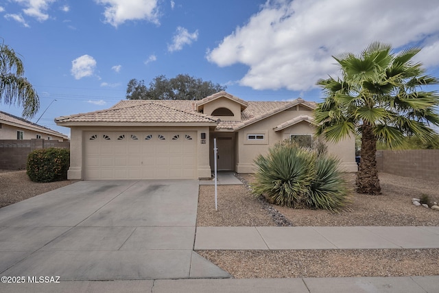 view of front of property featuring stucco siding, an attached garage, fence, driveway, and a tiled roof