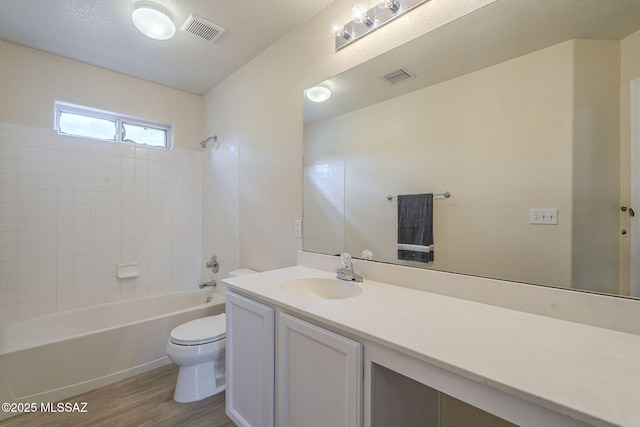 bathroom featuring toilet, visible vents, tub / shower combination, and wood finished floors