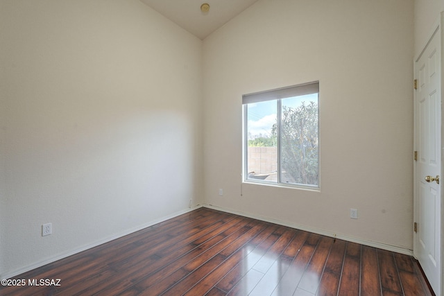 unfurnished room with dark wood-style floors, baseboards, and vaulted ceiling