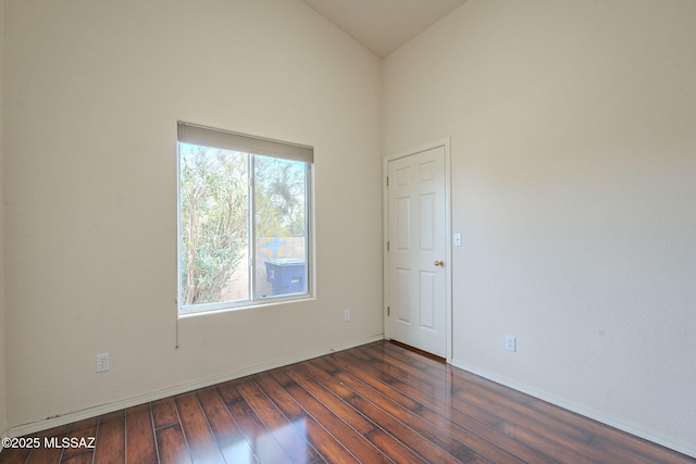 spare room featuring high vaulted ceiling, baseboards, and wood finished floors