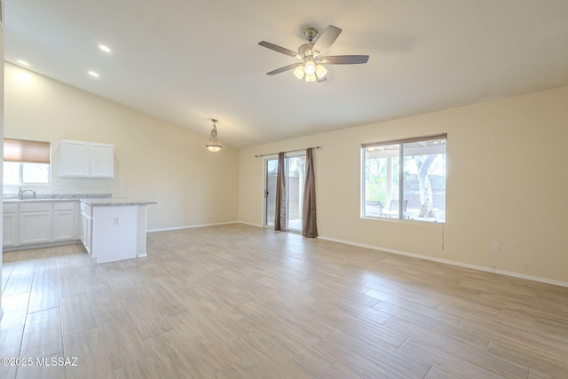 unfurnished living room featuring lofted ceiling, ceiling fan, light wood-style flooring, and baseboards