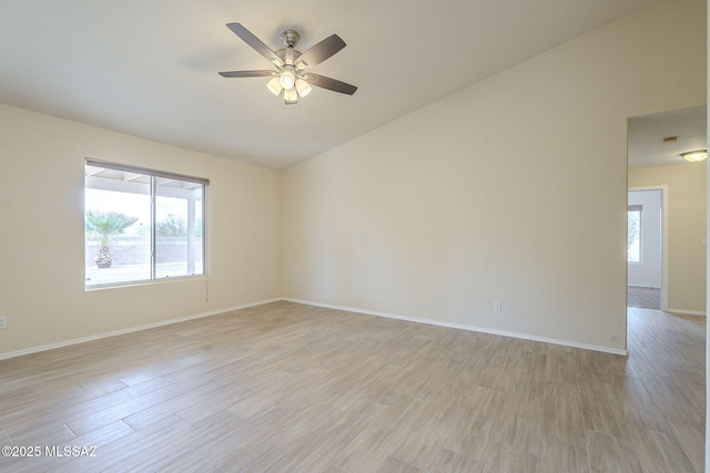 empty room with light wood-style floors, vaulted ceiling, baseboards, and a ceiling fan