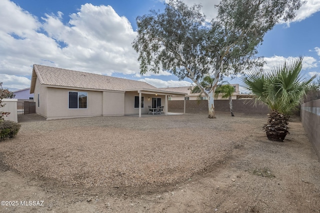 back of property with a fenced backyard, a patio, a tiled roof, and stucco siding