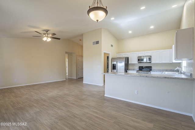 kitchen with visible vents, open floor plan, a peninsula, stainless steel appliances, and a sink