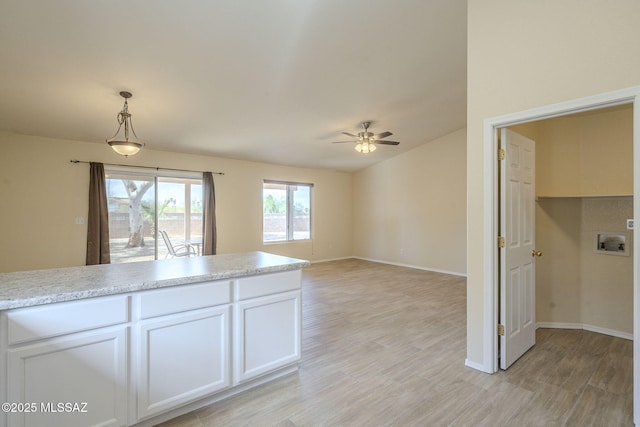 kitchen featuring light countertops, hanging light fixtures, light wood-style flooring, and white cabinetry