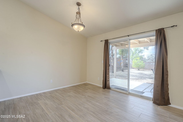 spare room with baseboards, lofted ceiling, and light wood-style floors