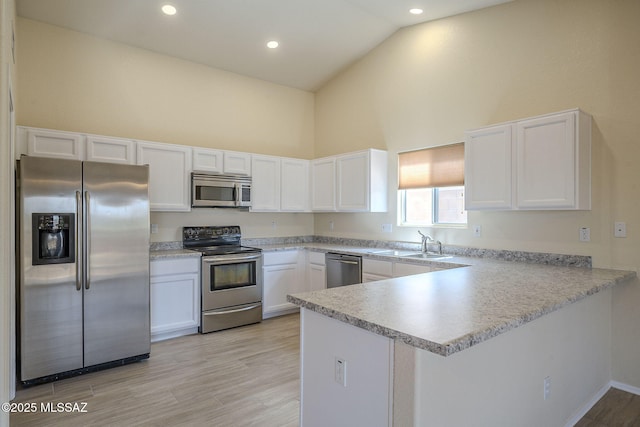 kitchen featuring white cabinets, appliances with stainless steel finishes, a peninsula, light countertops, and a sink