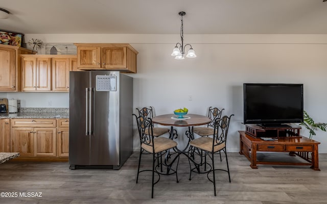 kitchen featuring light wood-style flooring, light stone countertops, an inviting chandelier, pendant lighting, and high end fridge