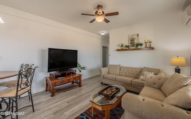 living room featuring baseboards, an AC wall unit, a ceiling fan, and light wood-style floors