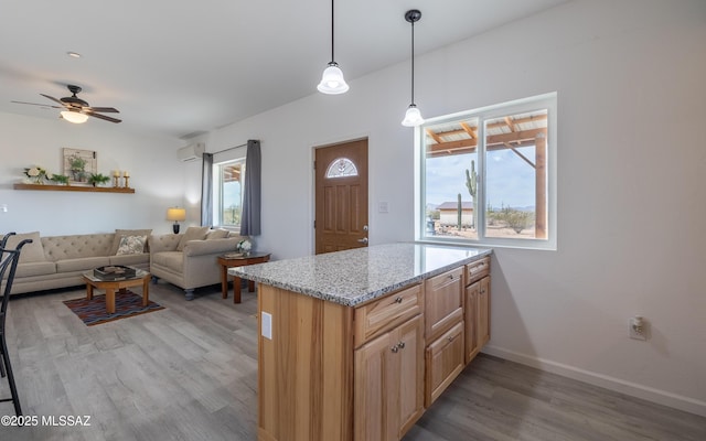 kitchen with an AC wall unit, plenty of natural light, light wood-style flooring, and baseboards