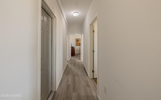 hallway featuring wood finished floors and baseboards