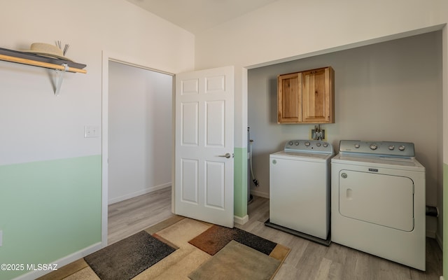 laundry room with cabinet space, baseboards, washer and clothes dryer, and light wood-style floors