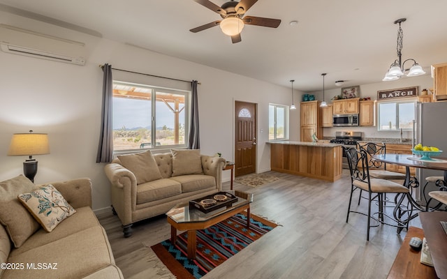 living room featuring light wood finished floors, a wall mounted air conditioner, and a healthy amount of sunlight