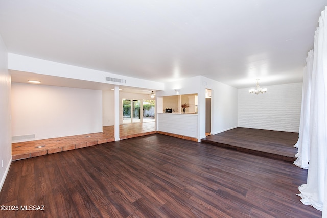 unfurnished room featuring dark wood-style floors, ceiling fan with notable chandelier, visible vents, and baseboards