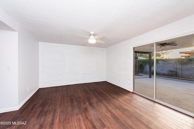 unfurnished room featuring a textured ceiling, brick wall, wood finished floors, and a ceiling fan