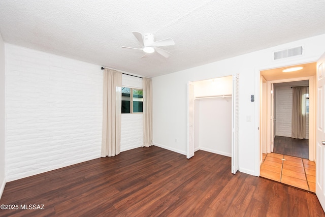 unfurnished bedroom with dark wood-style flooring, visible vents, ceiling fan, a textured ceiling, and baseboards