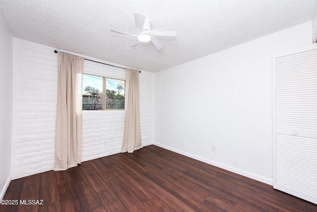 spare room with baseboards, a ceiling fan, dark wood finished floors, and a textured ceiling