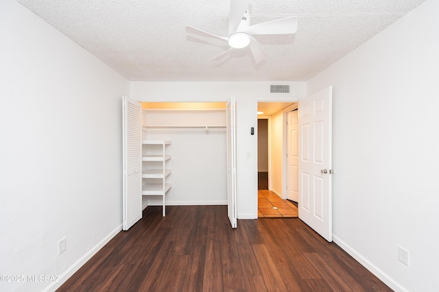 unfurnished bedroom with baseboards, visible vents, wood finished floors, a textured ceiling, and a closet