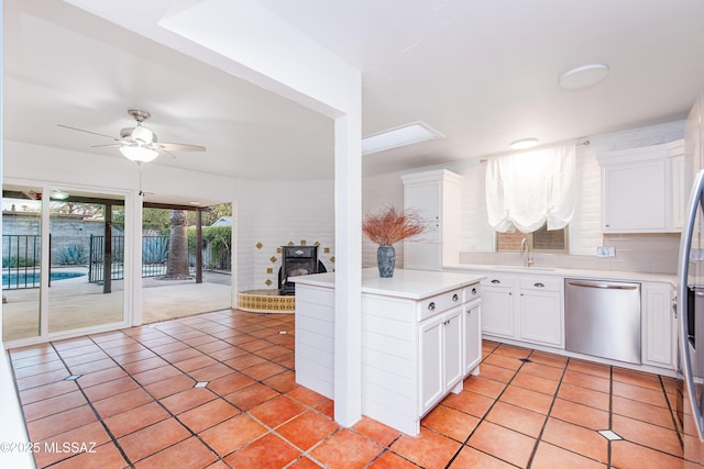 kitchen featuring light countertops, white cabinets, a sink, light tile patterned flooring, and dishwasher