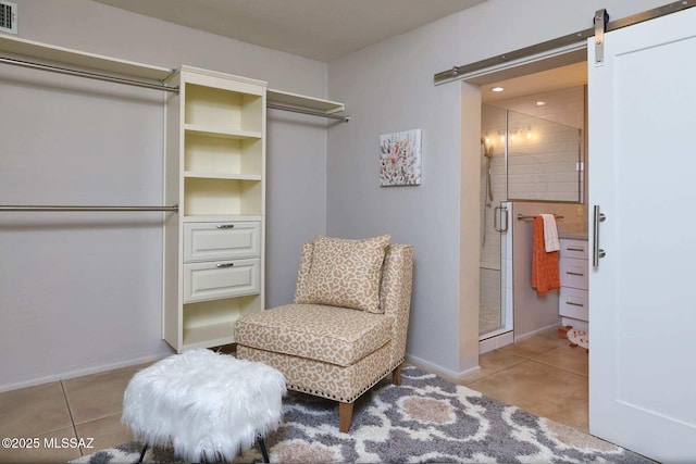 sitting room with tile patterned flooring, visible vents, baseboards, and a barn door