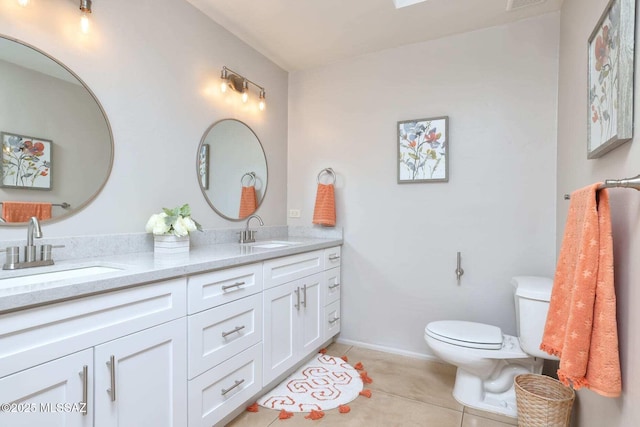 full bathroom featuring toilet, double vanity, a sink, and tile patterned floors