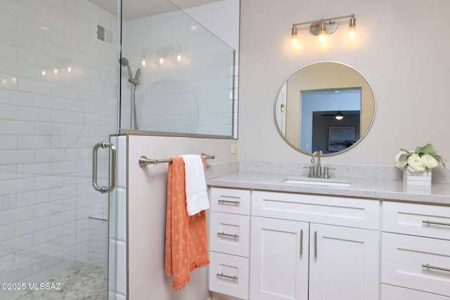 bathroom with visible vents, a shower stall, and vanity
