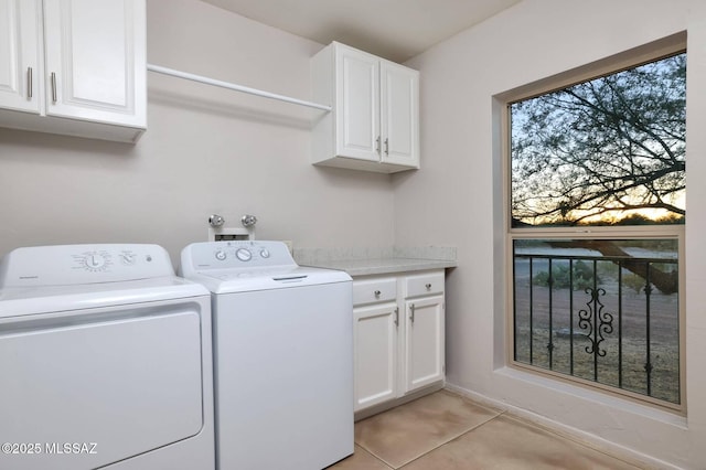 washroom featuring washing machine and clothes dryer, cabinet space, and light tile patterned floors