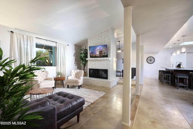 living area with a brick fireplace, light tile patterned flooring, and vaulted ceiling