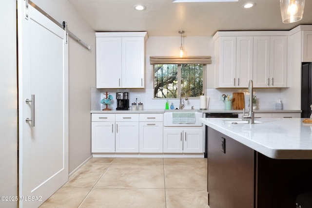 kitchen with white cabinets, a barn door, backsplash, and a sink