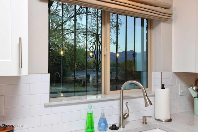 room details featuring a sink, white cabinets, and decorative backsplash