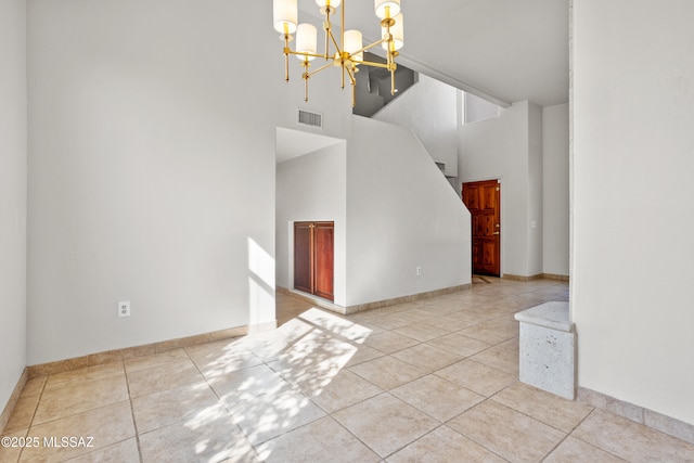 unfurnished living room featuring tile patterned flooring, visible vents, stairway, a high ceiling, and an inviting chandelier