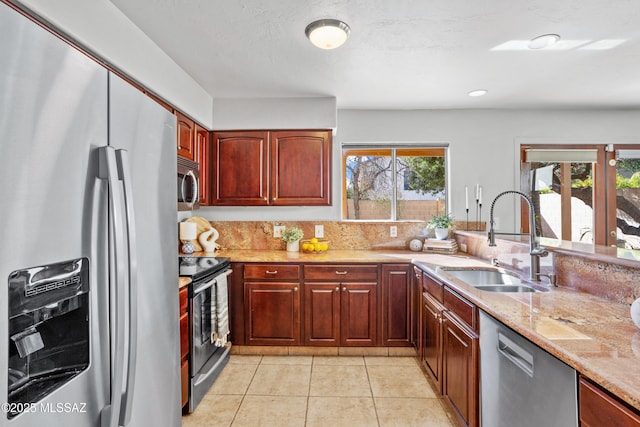 kitchen with light stone countertops, light tile patterned floors, a sink, and appliances with stainless steel finishes