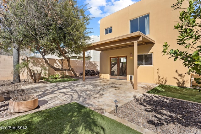 rear view of property featuring stucco siding, a patio, and a fenced backyard