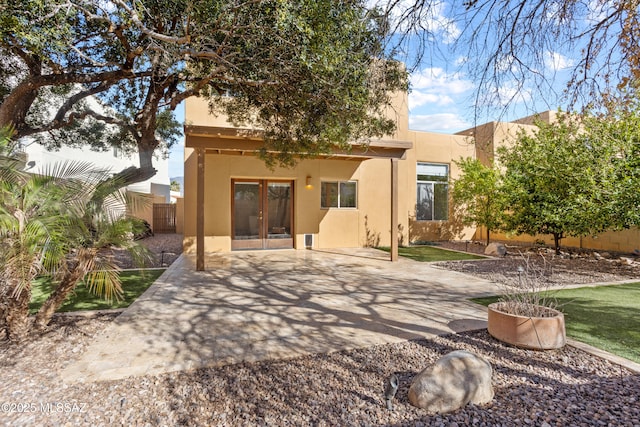 rear view of house with a patio area, stucco siding, and fence