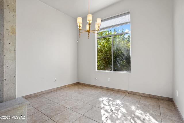empty room featuring a chandelier, light tile patterned floors, and baseboards