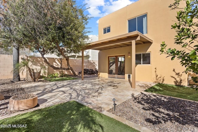 rear view of house with a patio area, stucco siding, and a fenced backyard