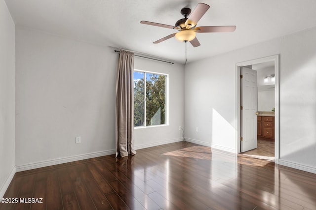 unfurnished bedroom featuring baseboards, ensuite bath, wood finished floors, and a ceiling fan