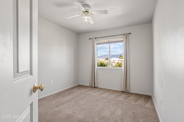 carpeted spare room with baseboards and a ceiling fan