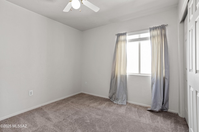 carpeted spare room with baseboards and a ceiling fan