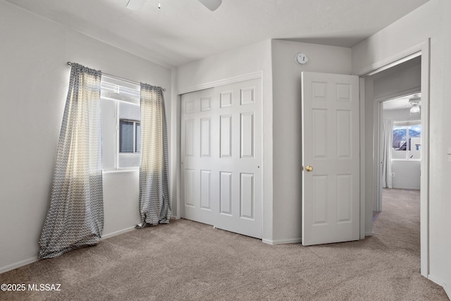 unfurnished bedroom with ceiling fan, carpet, a closet, and baseboards