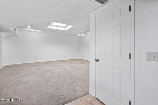 basement featuring light carpet, light tile patterned floors, a textured ceiling, and visible vents