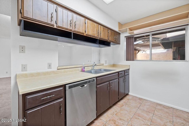 kitchen featuring light countertops, stainless steel dishwasher, light tile patterned flooring, a sink, and baseboards