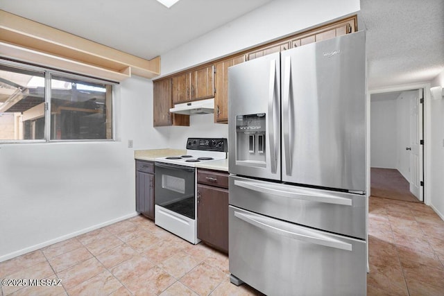 kitchen featuring electric stove, light countertops, stainless steel fridge, under cabinet range hood, and baseboards