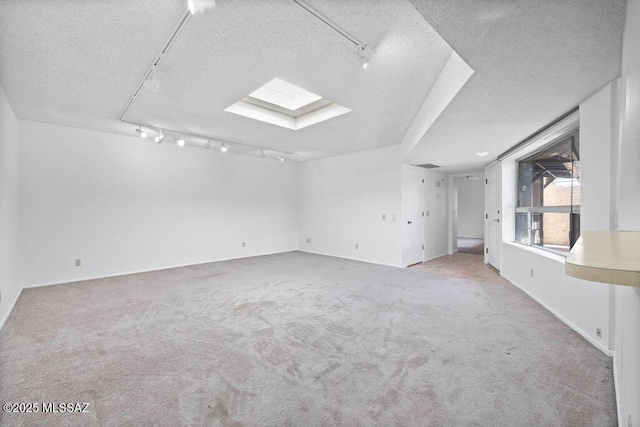 carpeted spare room with a skylight, track lighting, visible vents, and a textured ceiling