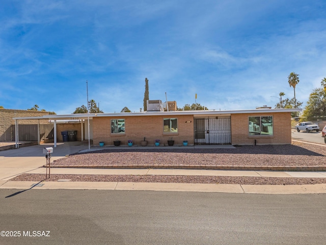 view of front of home with an attached carport, brick siding, fence, and driveway