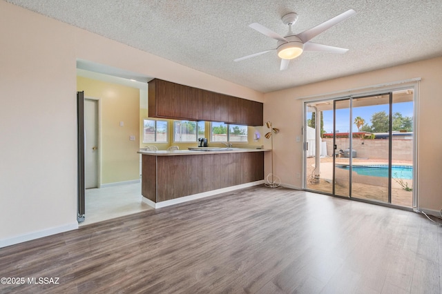 kitchen featuring ceiling fan, light countertops, a peninsula, and wood finished floors