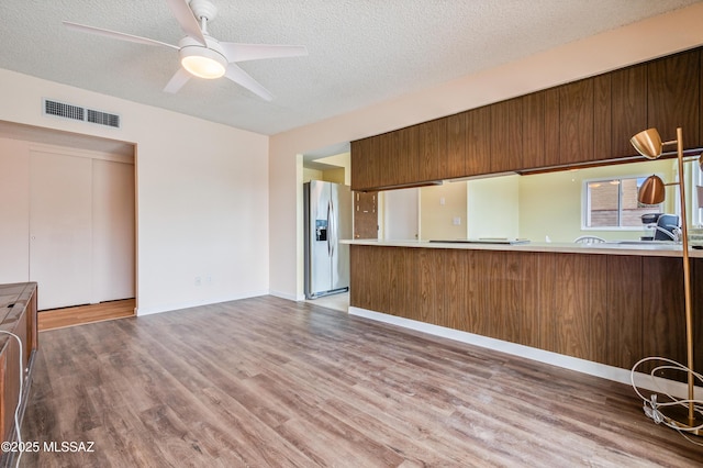 unfurnished living room with visible vents, a textured ceiling, and wood finished floors