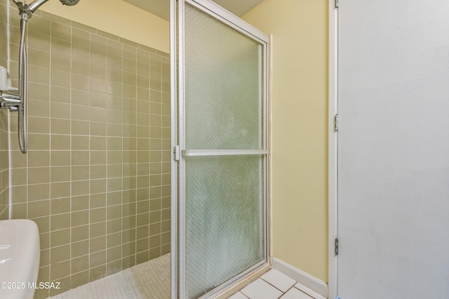 full bathroom featuring tile patterned flooring, toilet, a shower stall, and baseboards