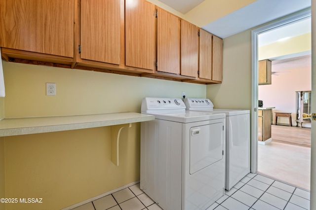 washroom featuring separate washer and dryer, light tile patterned flooring, and cabinet space